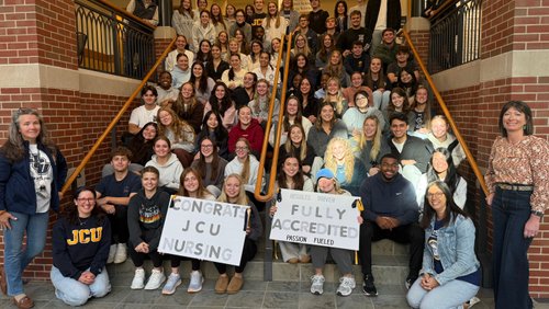 Joyful nursing students celebrate their program’s full accreditation on a university staircase