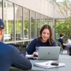 Two Students Sit Table Outside Building One Smiling