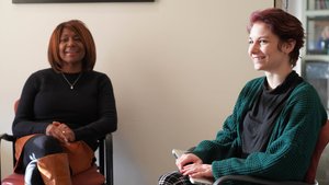 Two Women Sit Chairs Facing Each Other One
