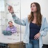 Young Woman Writes Mathematical Equations Glass Board Another